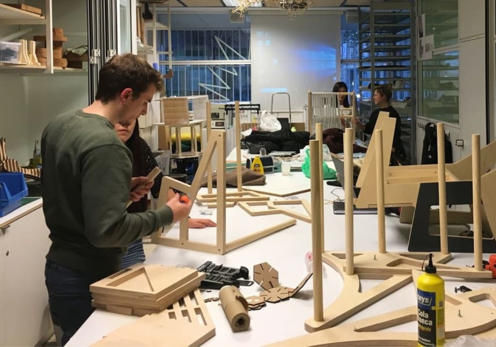 Students collaboratively constructing a wooden structure in a workshop.