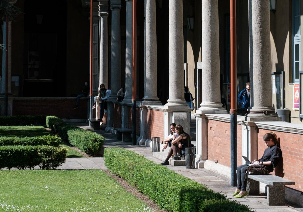 People relaxing on benches in front of a building.