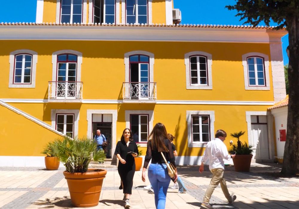 Individuals walking in front of a yellow building.